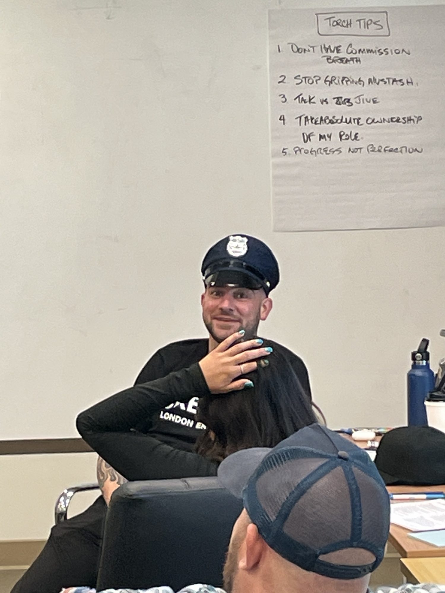 A participant in a police hat laughing with the group.